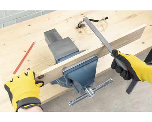 Pracovný stôl so zverákom, drevený kus, pilník, ceruzka, ochranné okuliare a pracovné rukavice