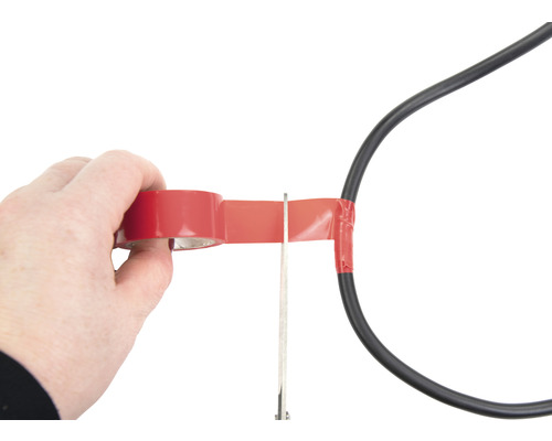 Osoba izoluje napájací kábel izolačnou páskou a nožnicami.