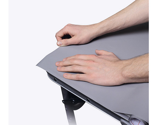 Osoba pripevňuje stolovú fóliu na stôl