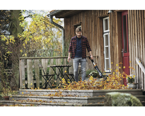 Muž používa vysávač lístia na drevenej terase na odstránenie lístia.