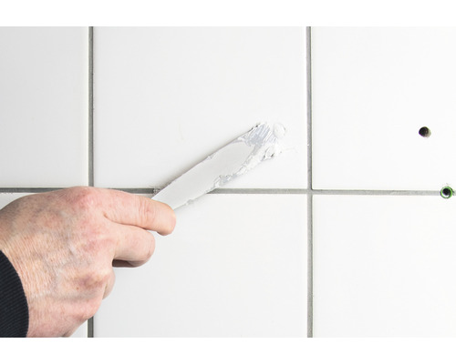 Aplikácia škárovacej hmoty špachtľou na dlaždice