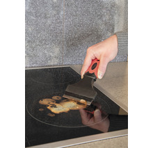 Osoba čistí varnú dosku pomocou škrabky na sklo.