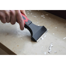 Remeselník používa škrabku na odstránenie zvyškov farby z povrchu.