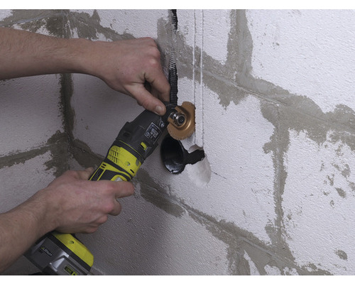 Muž pracuje na stene s multifunkčným nástrojom pre inštalatérske práce