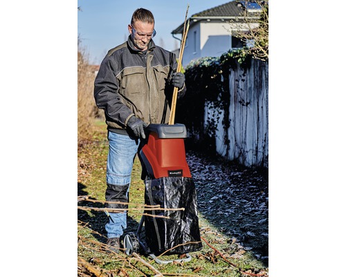 Osoba používa záhradný drvič na drvenie konárov a konárikov.