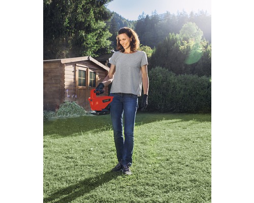 Žena používa elektrické nožnice na trávu v záhrade.
