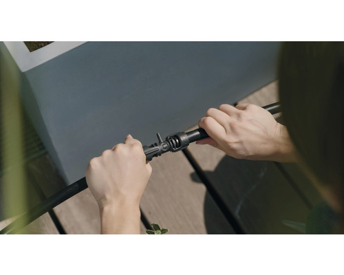 Osoba pripája zavlažovaciu hadicu ku konektoru.