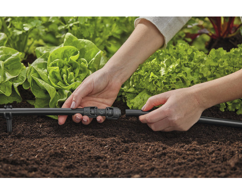 Osoba pripája zavlažovací systém v záhrade