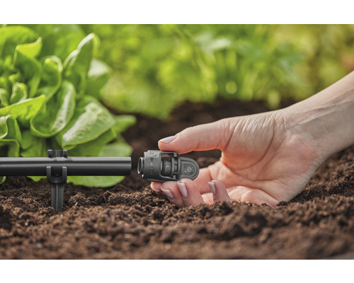 Detailný záber osoby pripevňujúcej konektor k zavlažovaciemu systému v záhrade