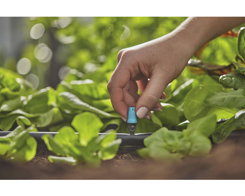 Detailný záber ruky upravujúcej zavlažovací systém v záhrade