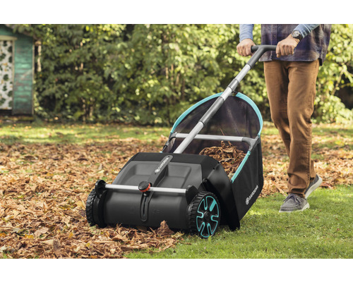 Osoba používa zberač lístia Gardena v záhrade na zber jesenného lístia.