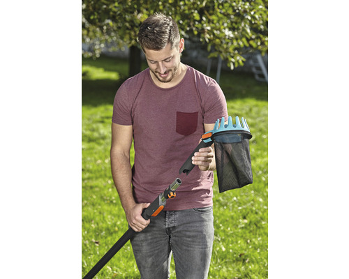 Muž pripája zberač ovocia k teleskopickej tyči v záhrade.