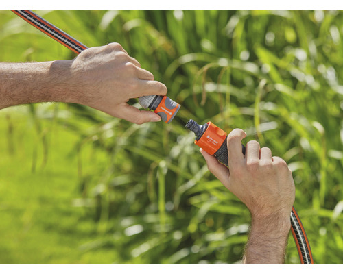 Dve ruky spájajú záhradnú hadicu pomocou hadicovej spojky.