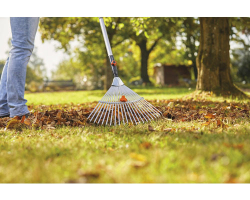 Osoba hrabe lístie hrabľami na lístie v záhrade.