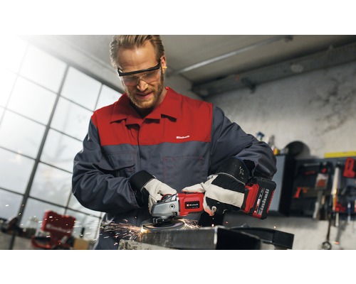 Muž brúsi kov akumulátorovou uhlovou brúskou Einhell v dielni.