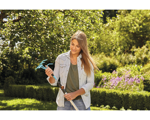 Žena drží nadstavec záhradných pazúrov s násadou v záhrade