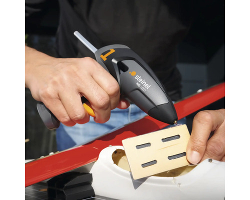 Osoba používa tavnú pištoľ Steinel MG 1007 na pripevnenie kusu dreva.