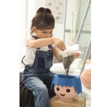 Dievča sype semená do kvetináča s tvárou