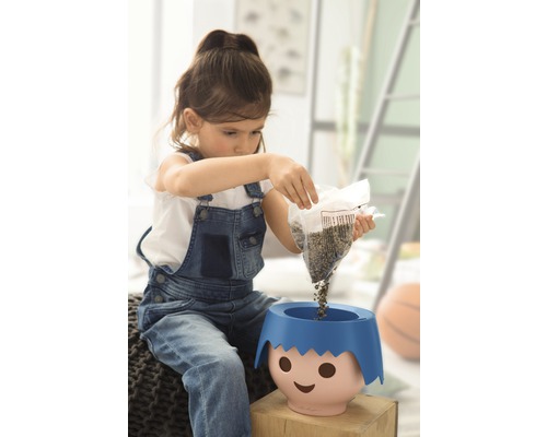 Dievča sype semená do kvetináča s tvárou