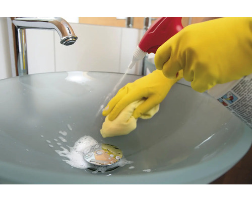 Čistenie kúpeľňového umývadla čistiacim prostriedkom a rukavicami