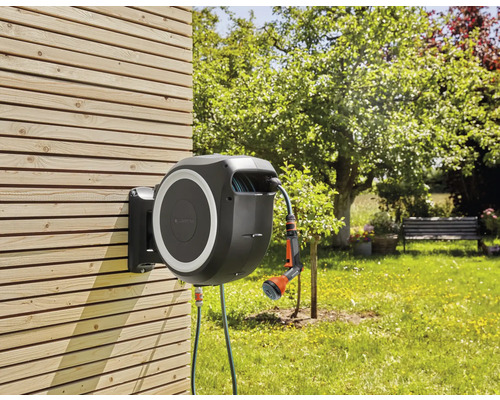 Box na záhradnú hadicu s hadicou a striekacou pištoľou na zavlažovanie záhrady, namontovaná na drevenej stene