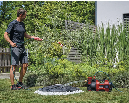 Muž zavlažuje záhradu záhradným čerpadlom a hadicou
