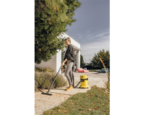 Žena vysáva lístie viacúčelovým vysávačom v záhrade