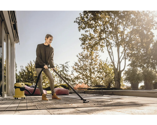 Žena vysáva terasu vonku pomocou viacúčelového vysávača