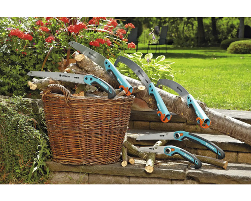 Rôzne ručné píly Gardena ležia s drevom v košíku