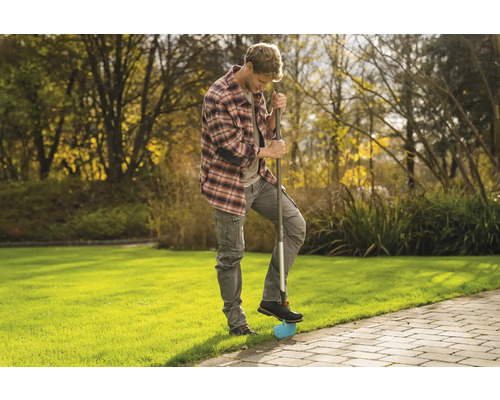 Muž používa v záhrade obrubník trávnika na úpravu okrajov trávnika