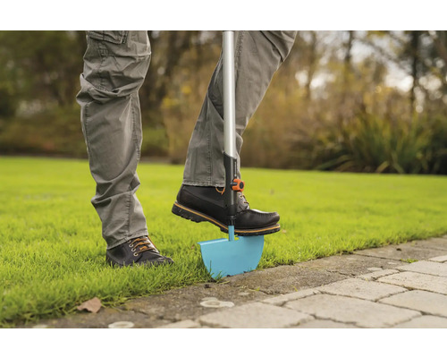 Osoba používa obrúbnik trávnika v záhrade.