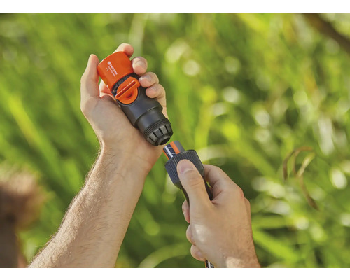 Osoba pripája Gardena vodnú stop spojku k záhradnej hadici.