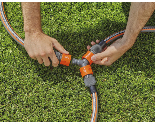 Osoba pripája záhradnú hadicu k rozdeľovaču na trávniku