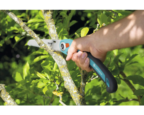 Práca v záhrade s orezávacou pílou pri prerezávaní konára stromu