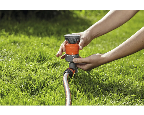 Osoba nastavuje zavlažovač trávnika na trávniku.