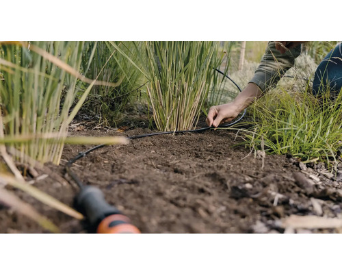Osoba inštaluje zavlažovací systém v záhrade.