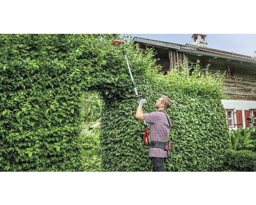 Muž strihá živý plot pomocou akumulátorových teleskopických nožníc na živý plot