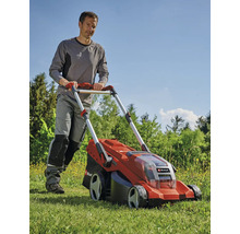 Muž tlačí červenú akumulátorovú kosačku na trávu v záhrade