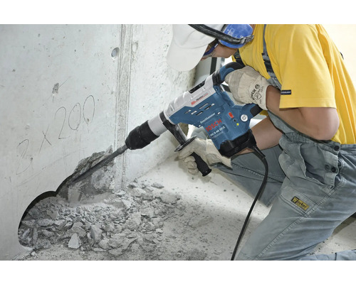 Robotník používa vŕtacie kladivo na vyvŕtanie otvoru do betónovej steny.