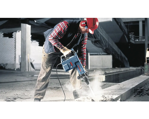 Robotník používa zbíjacie kladivo na stavenisku na rozbíjanie betónu.