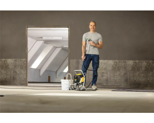 Muž s lakovacou pištoľou v prázdnej miestnosti