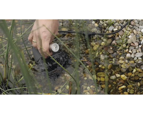 Ruka umiestňuje podvodnú lampu do jazierka