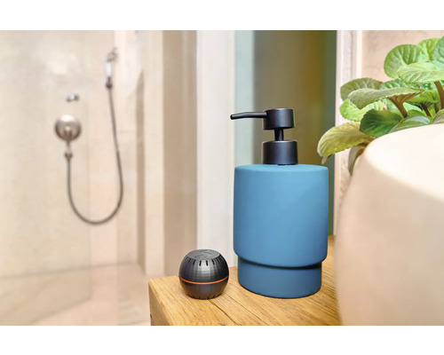 Kúpeľňová scéna s dávkovačom mydla a aromaterapeutickým difuzérom na drevenom stole