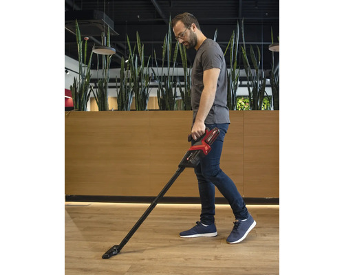Muž vysáva podlahu akumulátorovým vysávačom.