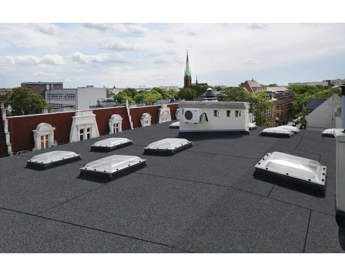 Strecha s bitúmenovými pásmi a strešnými oknami v mestskej scenérii