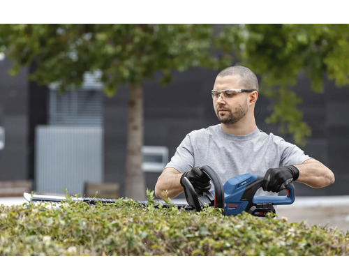 Muž strihá živý plot nožnicami na živý plot od spoločnosti Bosch