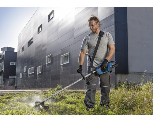 Muž strihá trávu s akumulátorovým vyžínačom v záhrade