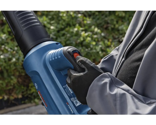 Osoba obsluhuje fúkač lístia v záhrade.