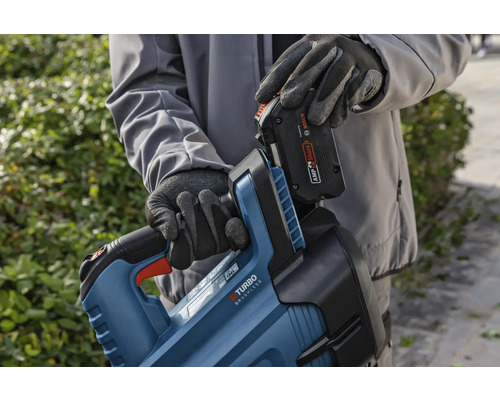 Osoba vkladá batériu do tela nožníc na živý plot.