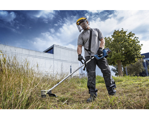 Osoba používa vyžínač s ochranným štítom v záhrade.